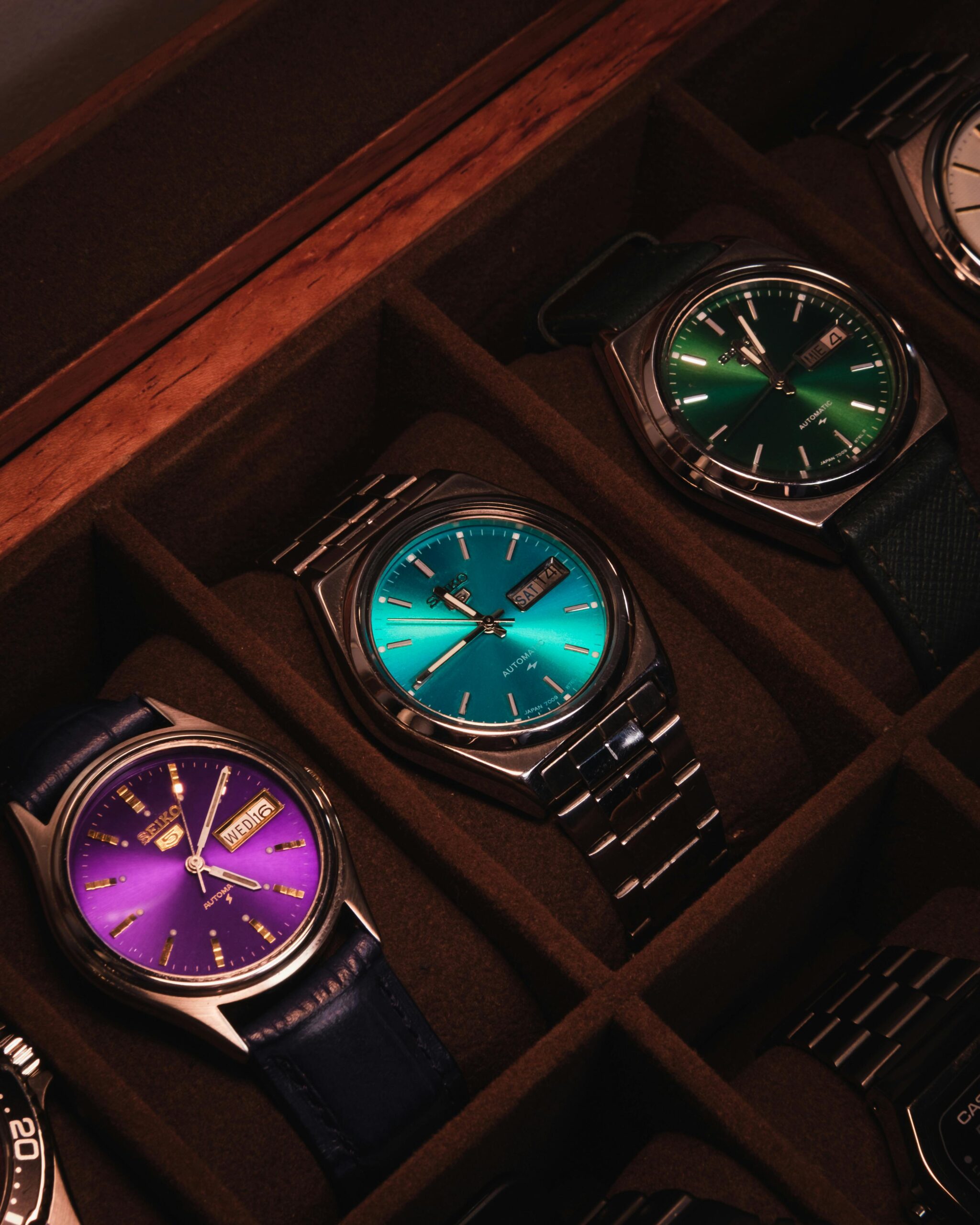 A stylish collection of colorful wristwatches neatly arranged in a wooden display case.
